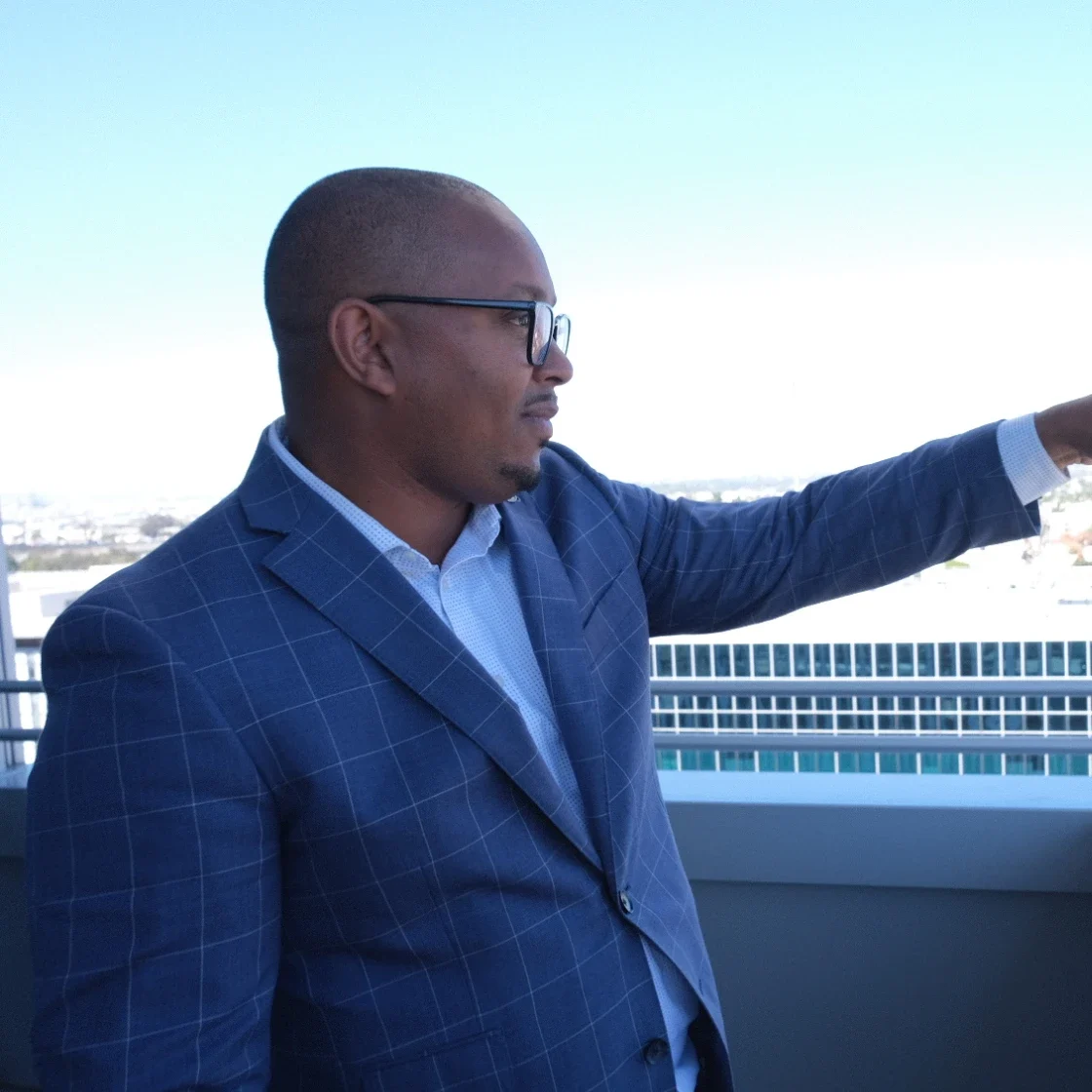 Rex Richardson stands on a balcony and points to a housing project.