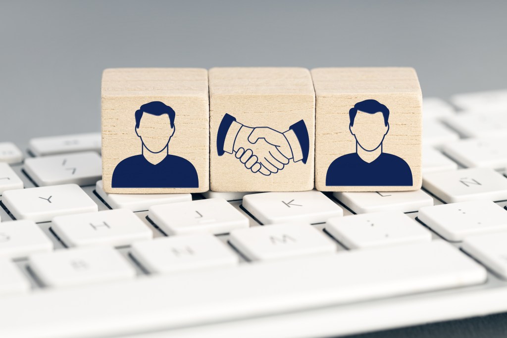Online Deal concept. Two human icon and handshake Icon on wooden blocks on computer keyboard