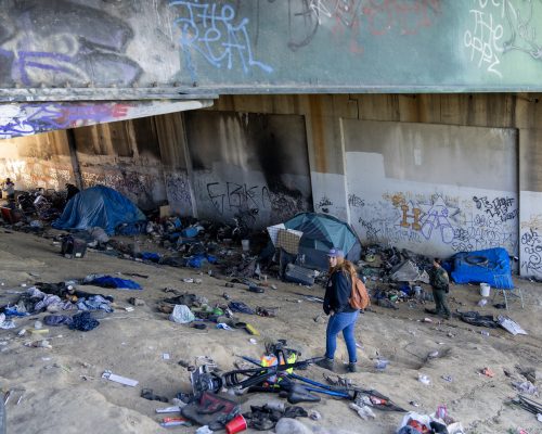outreach workers are seen under a graffiti-covered bridge in Los Angeles